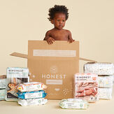 Baby in diaper box with diapers on floor surrounding