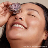 Woman wearing CCC tinted moisturizer and holding a succulent to her face