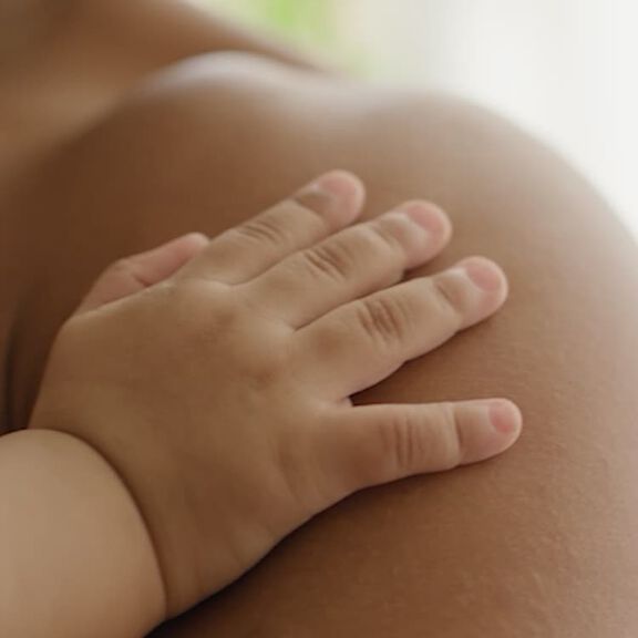 babys hand on mothers shoulder