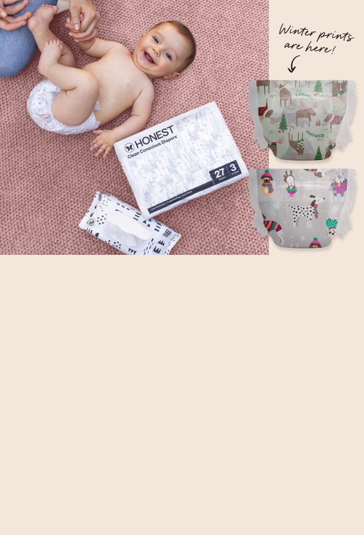 Toddler laying down on blanket next to a pack of Honest Diapers and Wipes. Imagery of 2 diaper prints