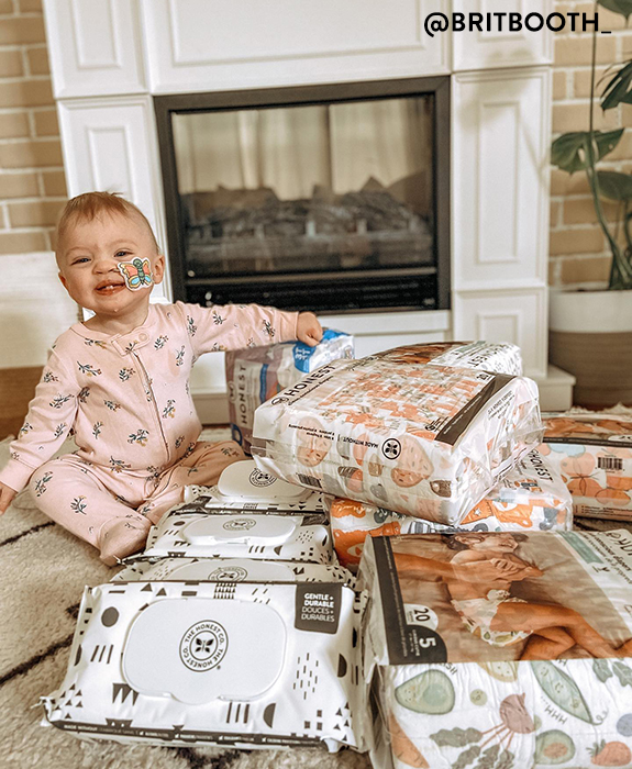 Baby sitting with honest diapers + wipes spread around