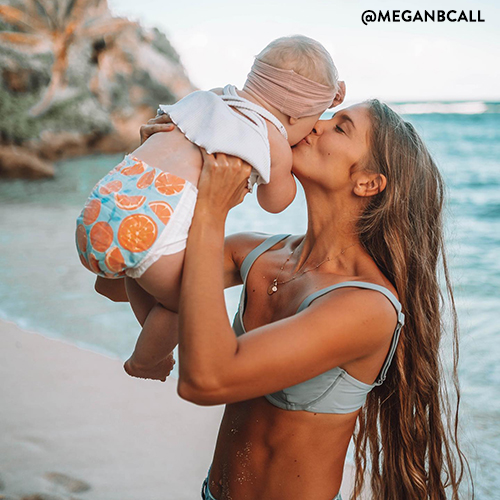 Woman holding baby wearing an honest diaper on beach