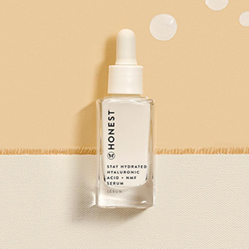 Vile of Honest Stay Hydrated Hyaluronic Acid + NMF Serum on a canvas background with product droplets