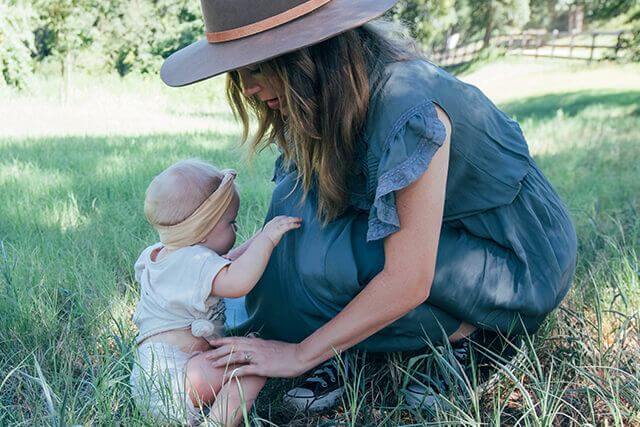 Mother playing with baby girl in grass