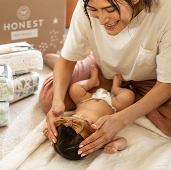 Woman playing with baby on bed.