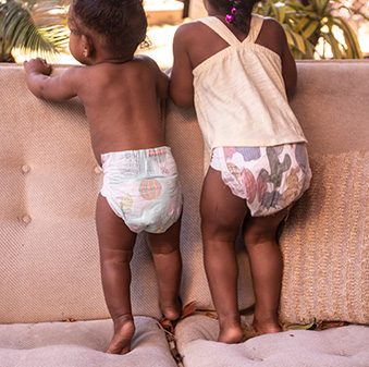 two babies playing on couch wearing Honest diapers.