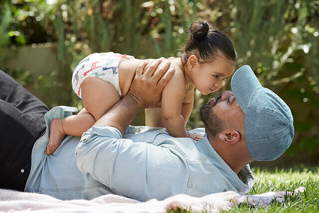 Father playing with baby girl in grass